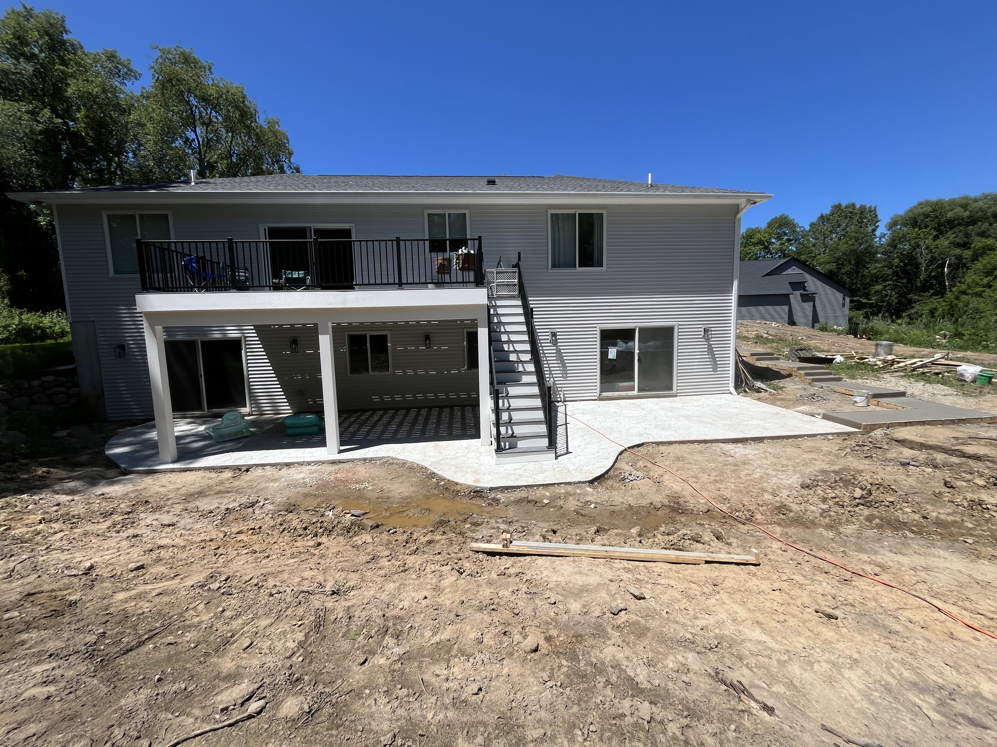 Completed backyard patio with stairs under second-story deck