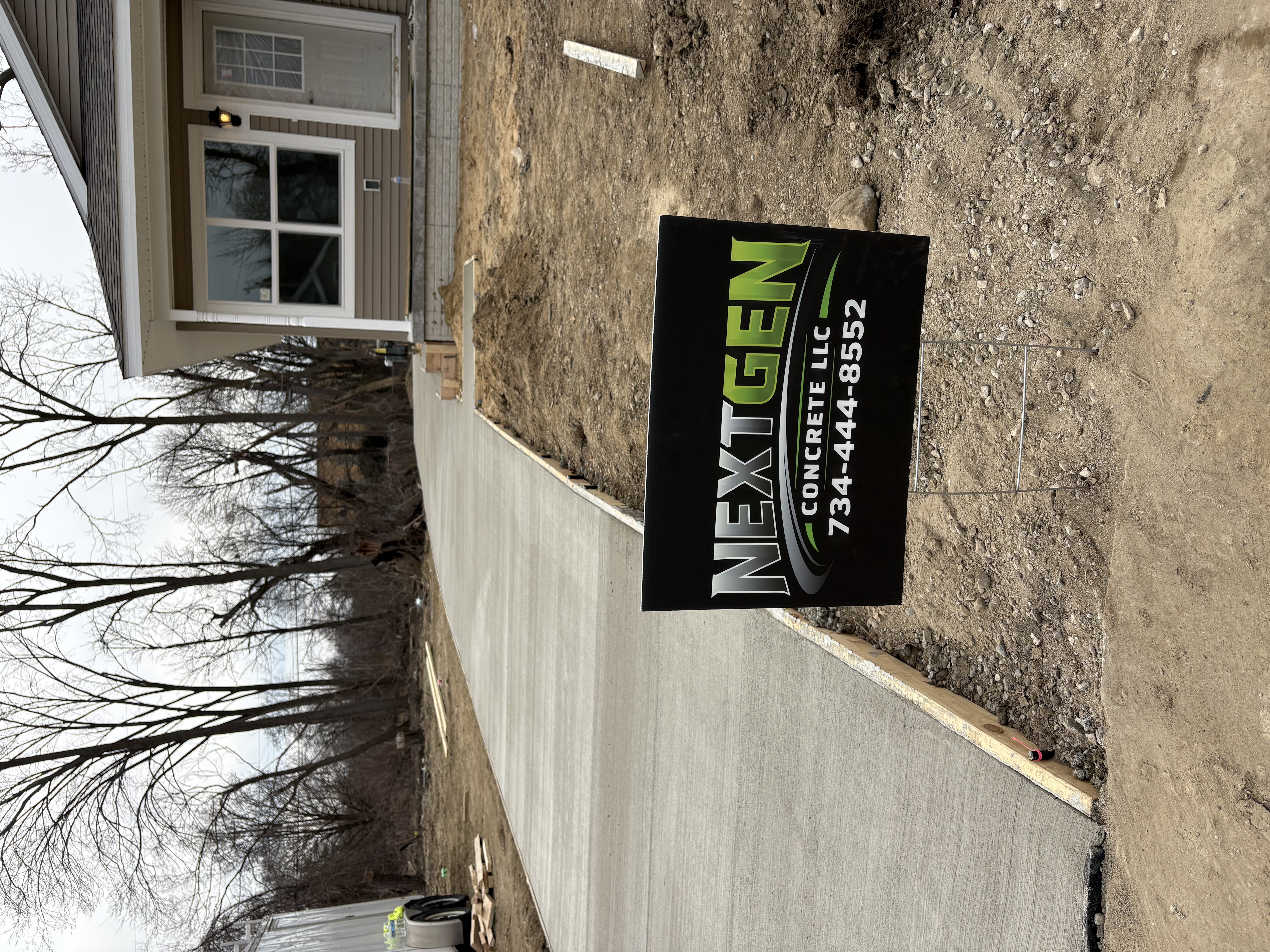 Fresh concrete sidewalk with NextGen Concrete yard sign