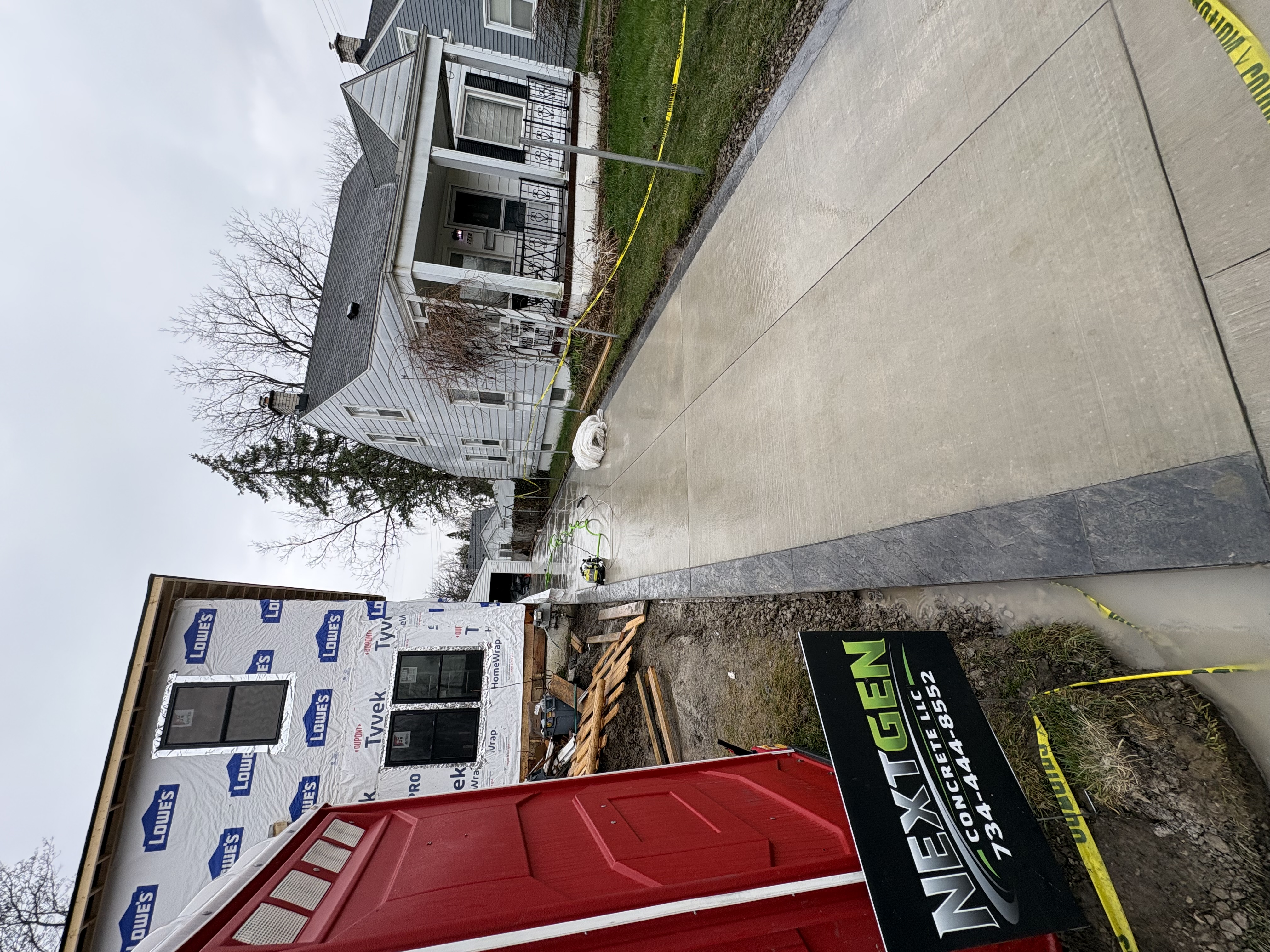 New concrete driveway at two-story home with NextGen sign