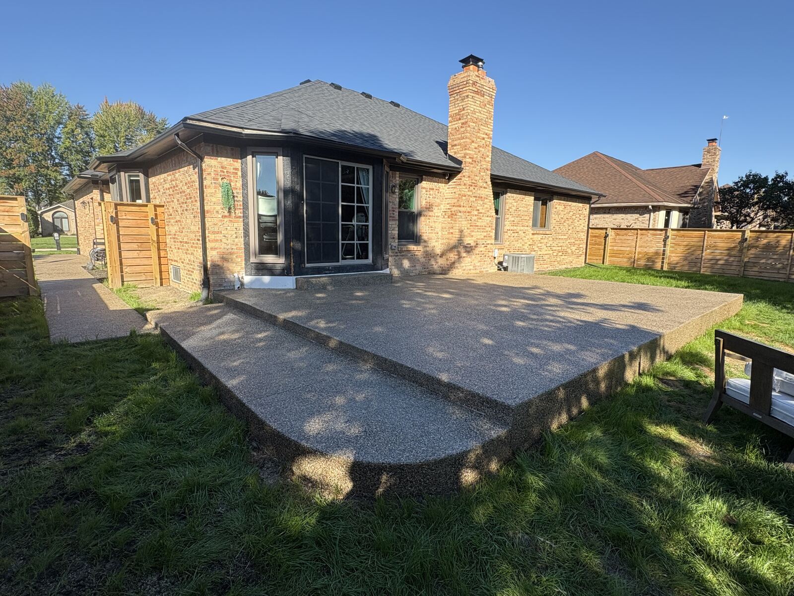 Raised exposed aggregate patio behind a brick ranch home