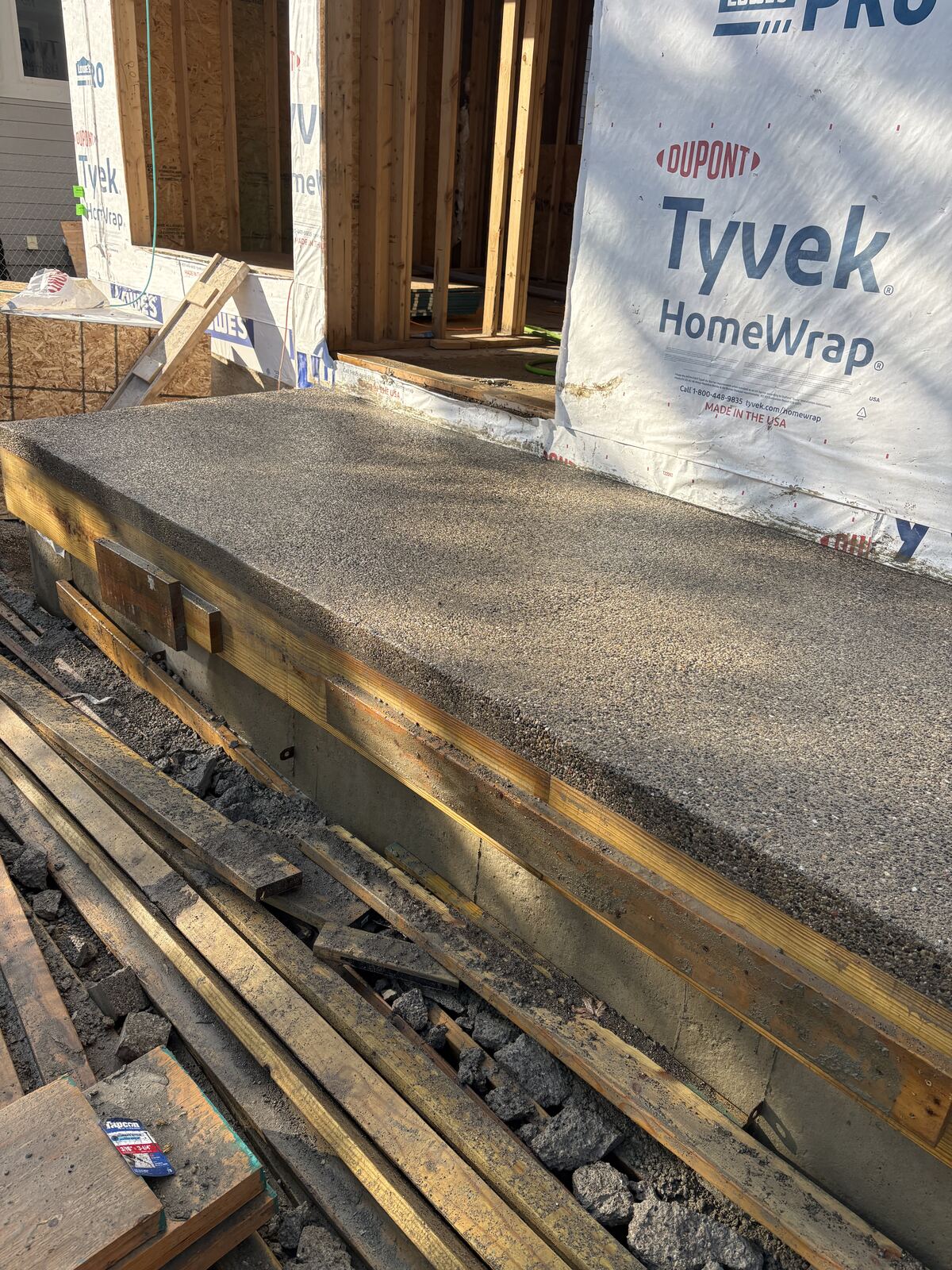 Freshly poured exposed aggregate porch slab at new construction
